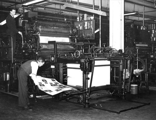 An old printing press with a man operating it