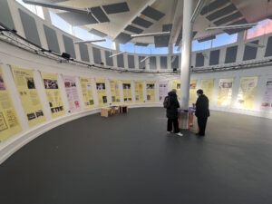 an exhibition installed in a round room, showing banners hanging around the outside wall.