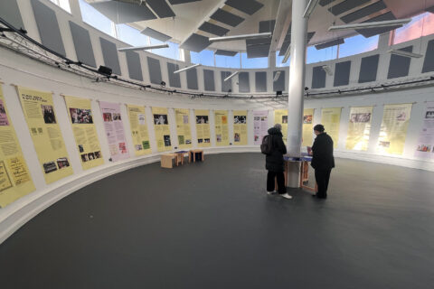 an exhibition installed in a round room, showing banners hanging around the outside wall.